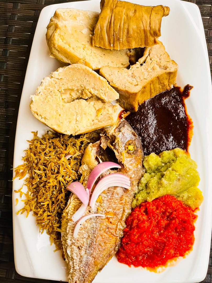 Kenkey served with fried fish, shito, green and red pepper sauces and shrimp